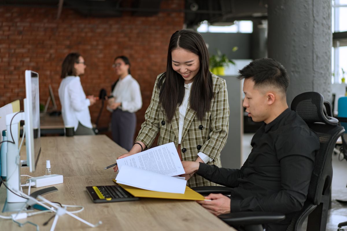 Two colleagues reviewing documents together at a desk